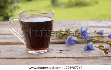 Close-up chicory drink on the wooden table in the garden at summer day. A bouquet of calendula flowers on the table. Herbal medicine concept