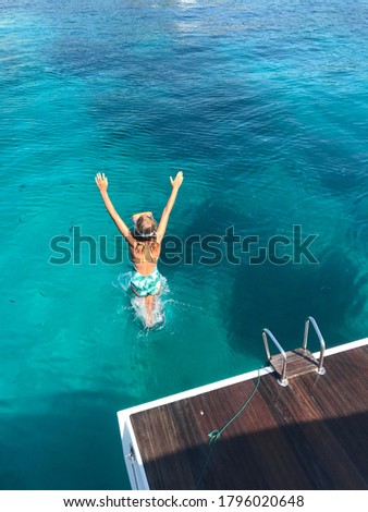 Young girl jumping into the turquoise water from the yacht. Mallorca, Balearic Islands