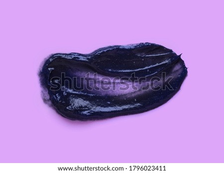 Smear of a black charcoal mask on purple isolated background. Smudge texture brush stroke.