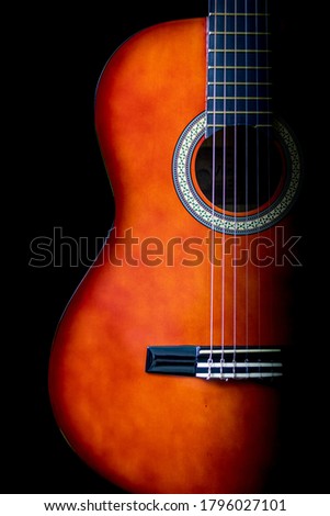 Low-key picture of a classical guitar with the key light on the left and the right in shadow. 