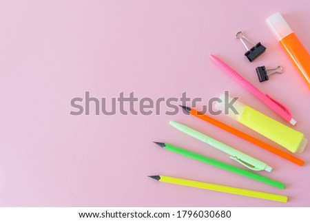 School supplies. Office items. Multicolored pencils, pens, markers and paper clips lie on a pink background at right. Back to school. Flat lay, copy space for text.