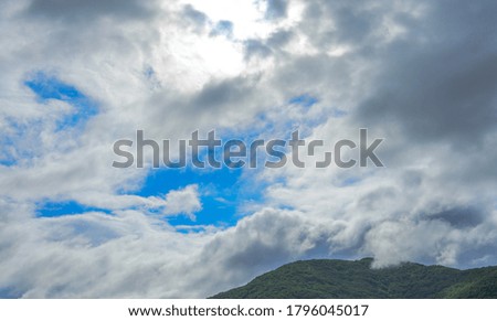 The blue sky with large volume clouds and tops of hills