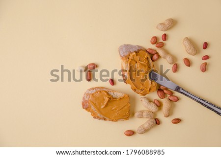 Peanut butter on bread, peanut sandwich, nuts
scattered across the table. Colored background. Copy space for your text