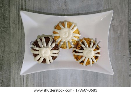 Mini muffin cakes with frosting on a white platter.