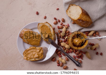 Peanut butter in a jar of bread on a white plate, a peanut butter sandwich, nuts scattered on the table. walnuts.