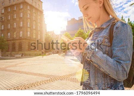 Selfie woman. Happy young girl with phone smile, typing texting and taking selfie in summer sunshine urban city. Pretty female taking fun self portrait photo. Vanity, social network concept.