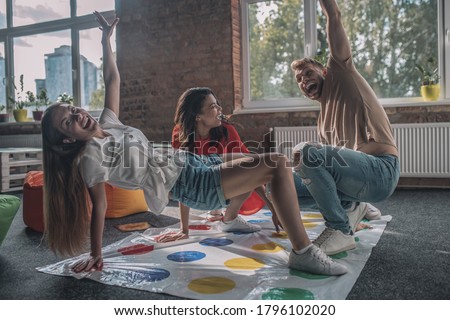 Playing on the floor. Three people having fun while playing twister game Royalty-Free Stock Photo #1796102020