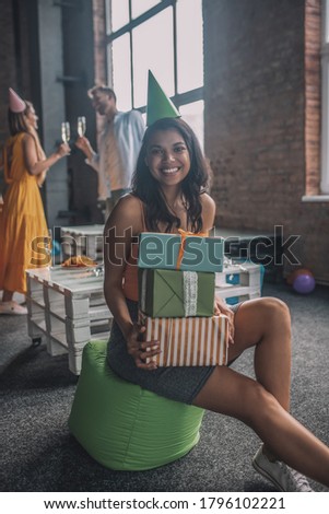 Celebration. A smiling woman holding a pile of birthday gifts