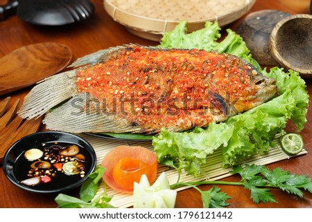 Fried fish sprinkled with hot chili sauce on a wooden table. Usually used for menu list pictures or food pictures in restaurants. Top view