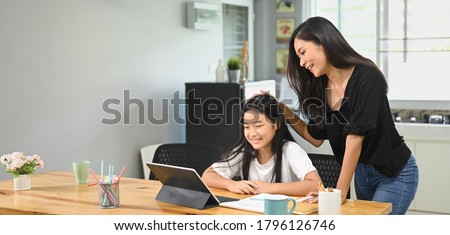 Home activity concept, Mother is teaching a daughter to do homework at home.