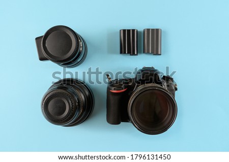 Photographer's equipment. Flat lay composition with photographer's equipment and accessories on yellow background.Camera, lenses and spare batteries on a blue background, top view.