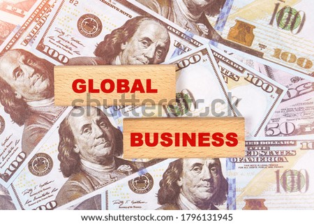 Business concept. Against the background of dollar bills, the text is written on wooden blocks - global business
