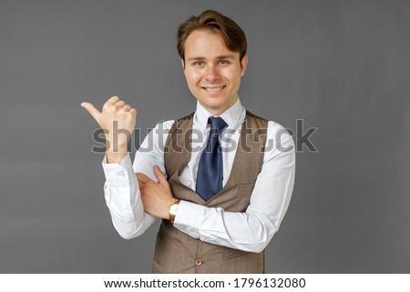 An emotional portrait of a businessman who shows a gesture of his hand to the right. Gray background. Business and finance concept