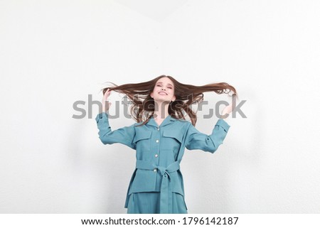 girl in a blue suit on a white wallbackground. Fashion catalog dynamic photography of a young brunette girl, on a background of white texture. Stylish every day office outfit. Free space for text
