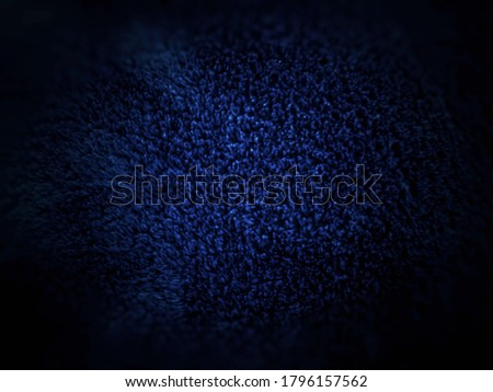 Close-up surface photo of dark blue towel with faded marks, blur mode shooting with low light. The abstract dark blue background texture for decorative design.