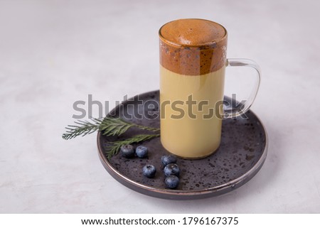Korean coffee Dalgona Original colors, colored milk in a glass cup on a dark background with a place for the text
