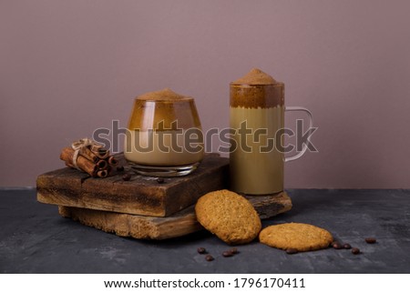Korean coffee Dalgona Original colors, colored milk with whipped foam in glass glasses on a dark background. Cookies, chocolate. Composition with coffee drinks. Dark 
 background with copy spac