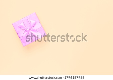 Gift wrapping, beautiful box of pink lilac color with bows from ribbons for the holiday on a beige peach background in pastel colors with copy space top view, flatlay