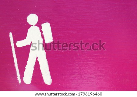 A closeup of a sign with a hiking stickman wearing a backpack
