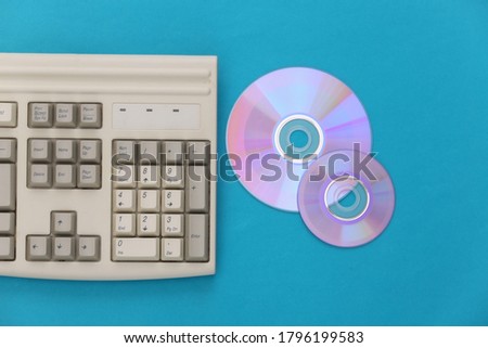 Retro electronics, pc technology 90s. PC keyboard, CD's on blue background. Top view