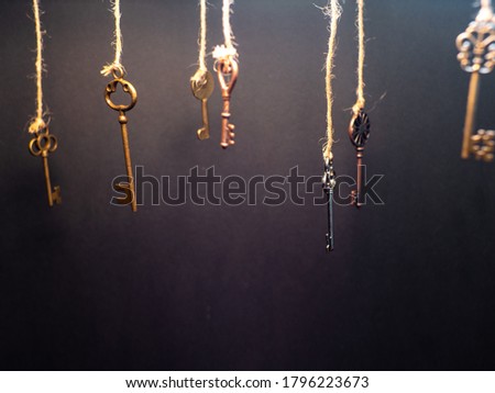 A lot of different old keys from different locks, hanging from the top on strings. Finding the right key, encryption, concept. Retro vintage brass keys on a dark background