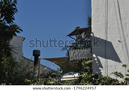 A low angle shot of a  "La Caleta" sign hanging on a  building wall