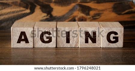 the word Aging wooden cubes with burnt letters. Seniors healthcate and mental health concept.