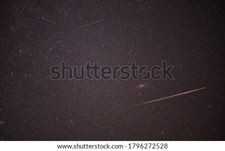 Meteor shower during perseid curent. Andromeda galaxy in night sky