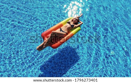 Summer Vacation. Enjoying suntan Woman in bikini on the inflatable mattress in the swimming pool.