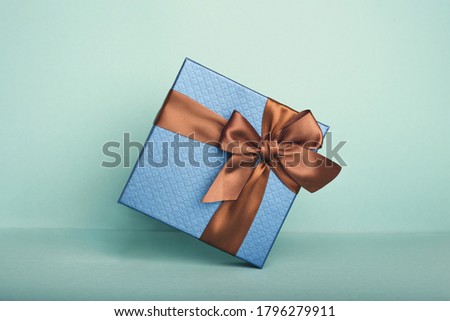 A blue gift with brown strip on the green background. Holiday concept.