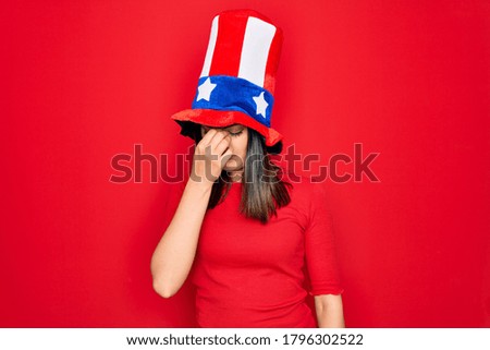 Young beautiful brunette woman wearing united states hat celebrating independence day tired rubbing nose and eyes feeling fatigue and headache. Stress and frustration concept.