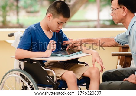 Special need child on wheelchair use a tablet in the house with his parent, Study or Work at home for safety from covid 19, Life in new normal education of special need kid,Happy disabled boy concept. Royalty-Free Stock Photo #1796320897