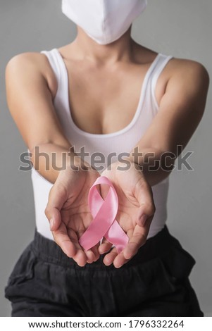 Woman hands holding pink ribbons and using face mask for breast cancer awareness, Breast cancer coronavirus. healthcare and medicine concept. Royalty-Free Stock Photo #1796332264