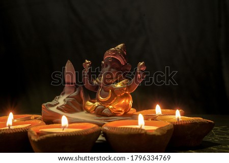 Ganesh or Ganesha elephant's head Hindu God with light from candles in the dark. Diwali is an Indian Hinduism candle festival. Decorated pray from fire to Gapati.