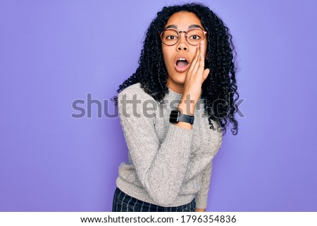 Young african american woman wearing casual sweater and glasses over purple background hand on mouth telling secret rumor, whispering malicious talk conversation