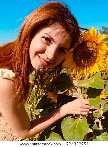 portrait of a girl with red hair and a cute smile holding a yellow sunflower in her hands