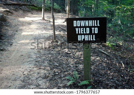 A mountain biking sign along a path says "Downhill Yield to Uphill".
