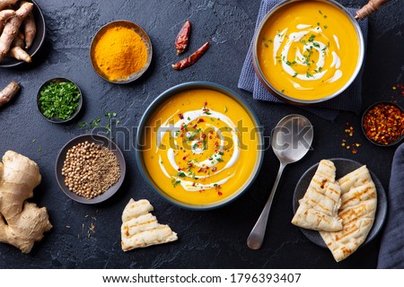 Pumpkin soup with spices in black bowl. Comfort detox food. Dark background. Top view. Royalty-Free Stock Photo #1796393407