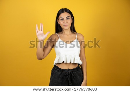 Young beautiful woman over isolated yellow background doing hand symbol