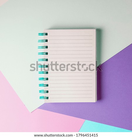 Open notebook with blank sheet and blue spiral on a colorful pastel background. The concept of education, writing down ideas, plans. Place for text. Minimalism, flat lay.
