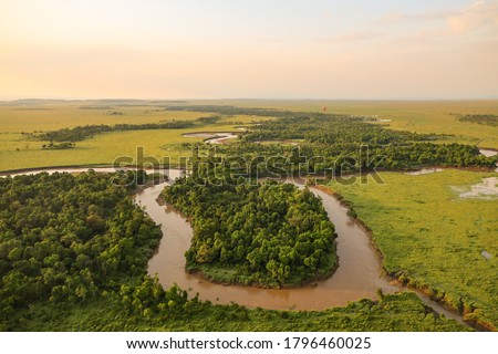 Aerial view from hot air balloon of beautiful African Serengeti savanna grassland landscape and flooded snaking serpentine Masai River in Masai Mara National Reserve, Kenya, Africa Royalty-Free Stock Photo #1796460025