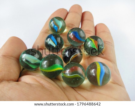Human hands hold many colorful marbles on white background.