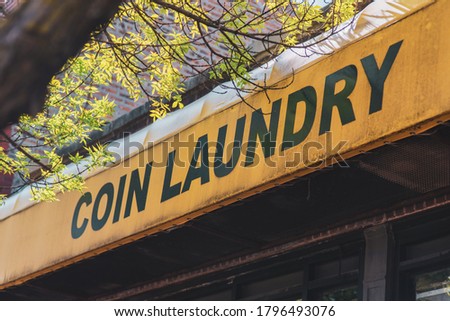 Coin Laundry Sign behind Tree branches in a yellow tint