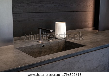 Dark beige marble wash basin with glossy metal mixer. White decorative vase. High quality photo