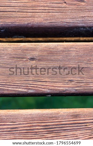 Wooden deck of a jetty in Lake Garda. The sun is reflected in the water. The wood is warm, brown in color. Detail, macro picture with bokeh.