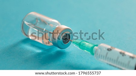 Vaccine, coronavirus vaccination, covid-19 flu prevention, immunization concept. Vial dose and medical syringe, drug medicine shot injection, pastel blue background, closeup.