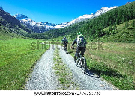 Couple of friends cyclists with mountain bikes in the mountains in beautiful landscape on the alps