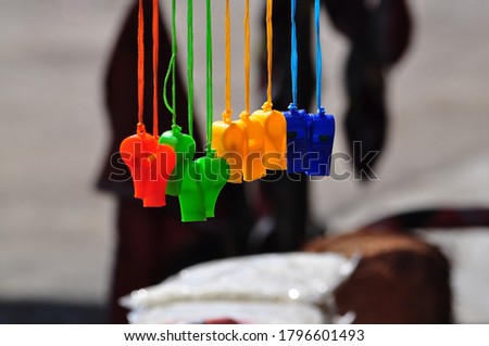 Colorful plastic toy whistles hang on display during an annual wrestling competition festival in the heritage village of Pragpur in Himachal Pradesh.