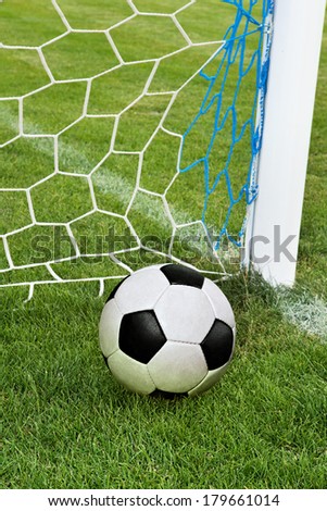 soccer ball in goal net with green grass 