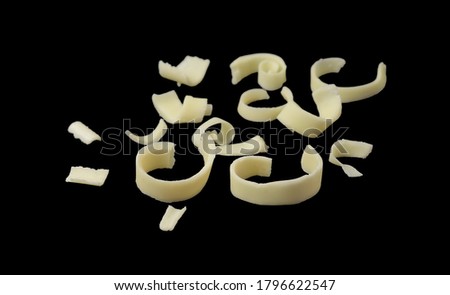 White Chocolate Curls Isolated On black Background. Group of chocolate shavings. Chocolate roll.